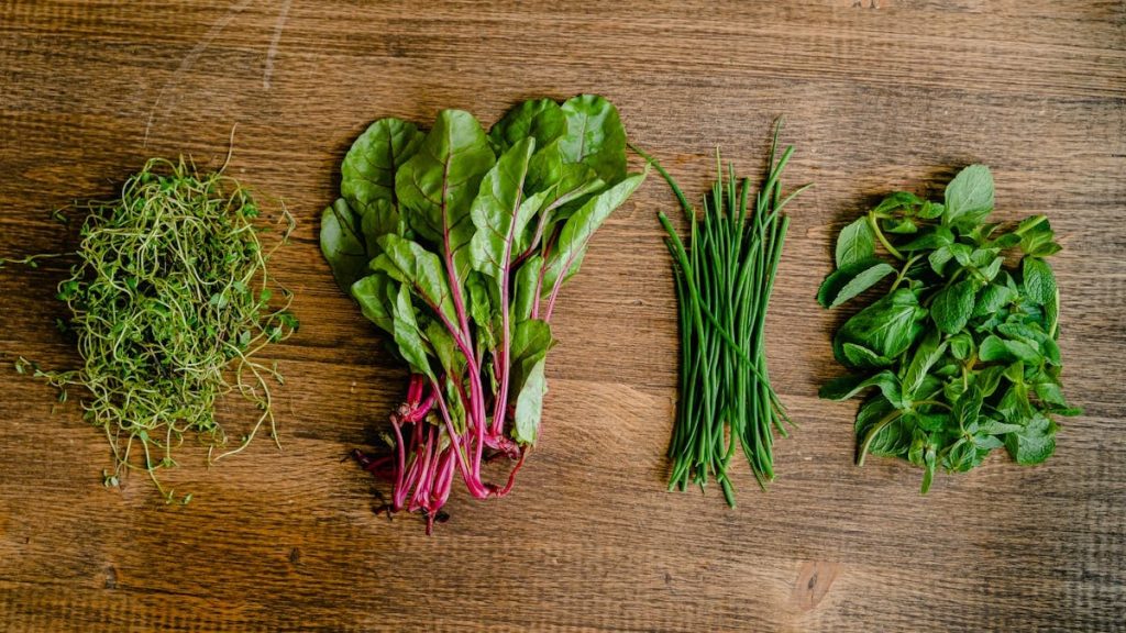 A vibrant selection of fresh herbs and greens neatly arranged on a wooden tabletop.